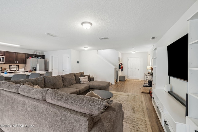 living room featuring light wood-type flooring and a textured ceiling