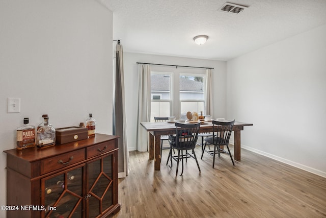 dining space featuring a textured ceiling and light hardwood / wood-style floors