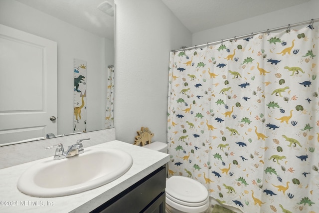 bathroom with a textured ceiling, toilet, vanity, and a shower with curtain