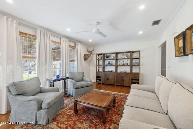 living room featuring hardwood / wood-style floors, ceiling fan, and crown molding