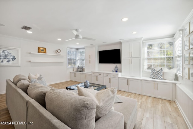 living room with light wood-type flooring, ceiling fan, and ornamental molding