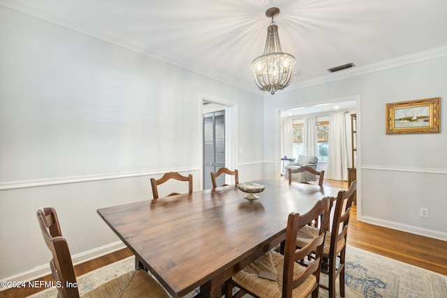 dining space with hardwood / wood-style flooring, ornamental molding, and a chandelier