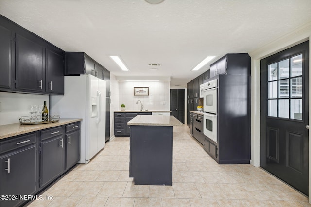 kitchen featuring decorative backsplash, a textured ceiling, a center island, and white appliances