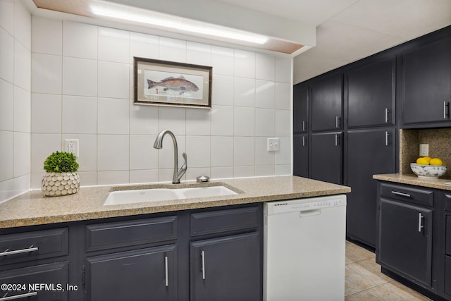 kitchen with decorative backsplash, light stone countertops, white dishwasher, sink, and light tile patterned floors