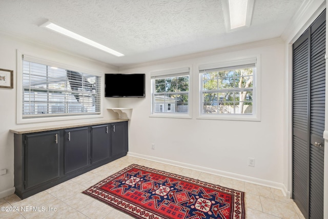 interior space featuring light tile patterned flooring, crown molding, and a textured ceiling