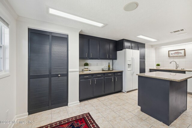 kitchen with crown molding, sink, light tile patterned floors, a kitchen island, and white fridge with ice dispenser