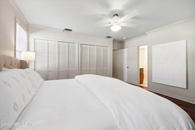 bedroom with wood-type flooring, two closets, ceiling fan, and ornamental molding