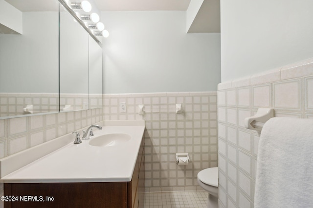 bathroom featuring tile patterned flooring, vanity, toilet, and tile walls