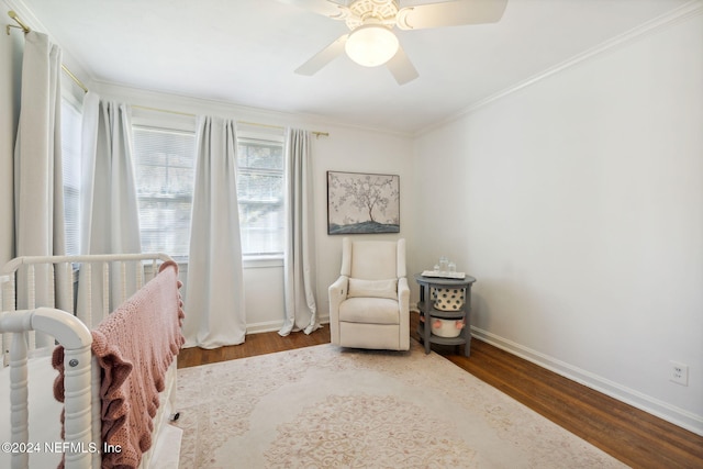 bedroom with hardwood / wood-style flooring, ceiling fan, ornamental molding, and a nursery area