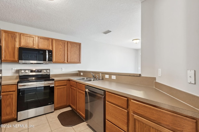 kitchen with a textured ceiling, light tile patterned flooring, sink, and appliances with stainless steel finishes