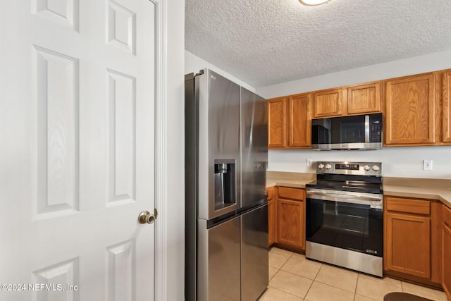 kitchen featuring light tile patterned flooring, stainless steel appliances, and a textured ceiling