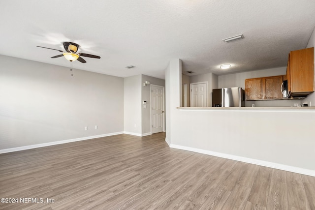 unfurnished living room with ceiling fan, wood-type flooring, and a textured ceiling