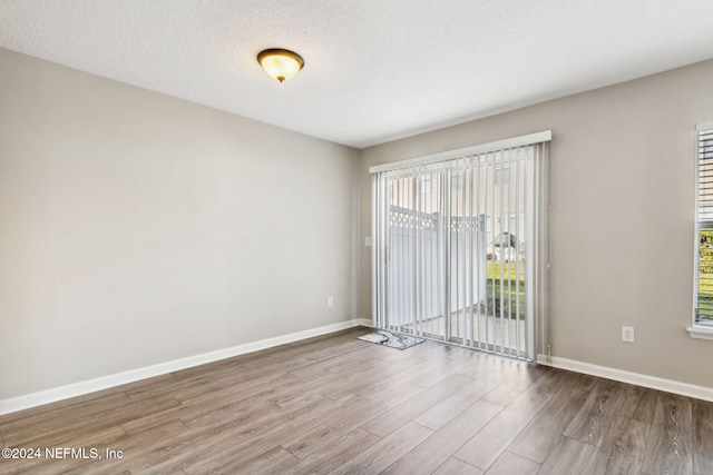 spare room with hardwood / wood-style floors, a healthy amount of sunlight, and a textured ceiling