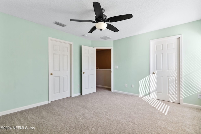 unfurnished bedroom with a textured ceiling, ceiling fan, and light carpet