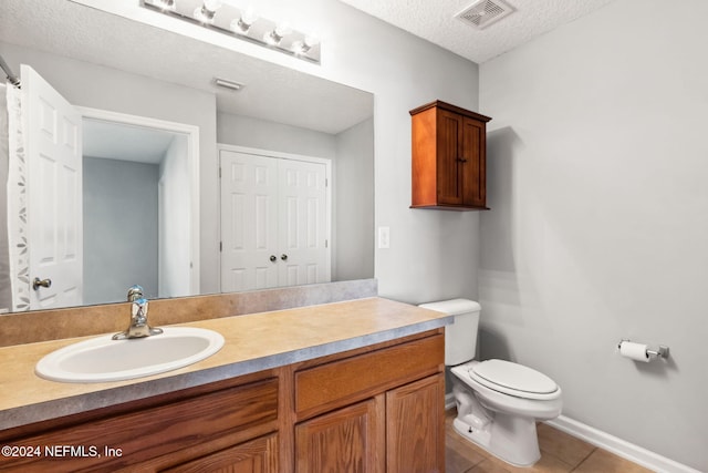 bathroom with tile patterned floors, vanity, toilet, and a textured ceiling