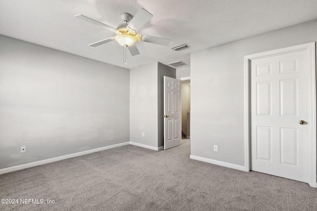 unfurnished bedroom with ceiling fan, light colored carpet, and a textured ceiling