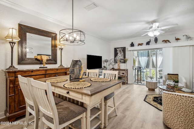 dining area with ceiling fan with notable chandelier, light wood-type flooring, and ornamental molding