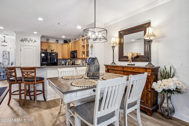 dining room featuring crown molding, a notable chandelier, and light wood-type flooring