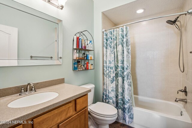 full bathroom featuring a textured ceiling, vanity, toilet, and shower / bath combo with shower curtain