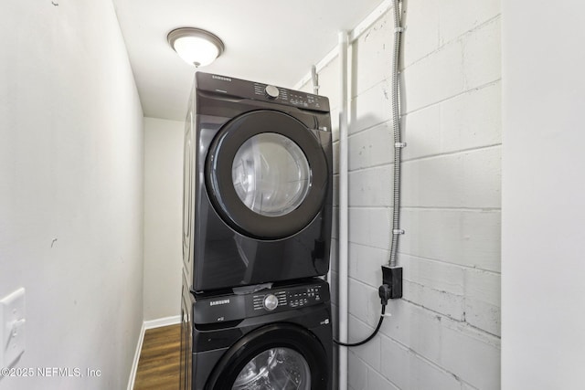 clothes washing area with stacked washer / dryer and dark wood-type flooring