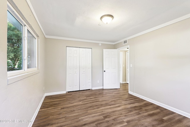 unfurnished bedroom with dark hardwood / wood-style floors, a closet, and ornamental molding