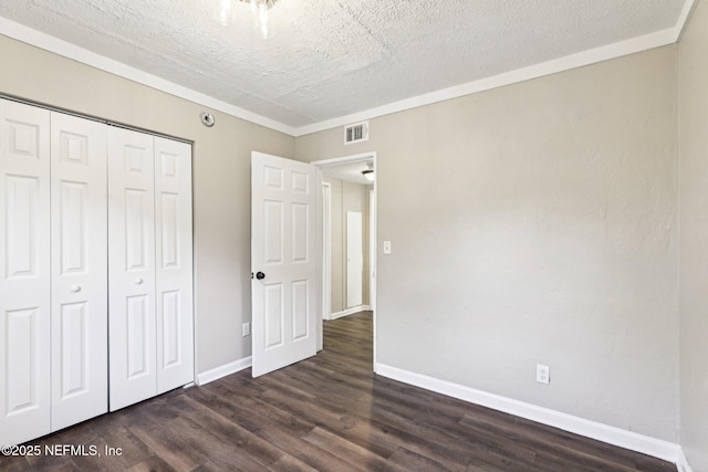 unfurnished bedroom featuring a textured ceiling, dark hardwood / wood-style floors, a closet, and ornamental molding