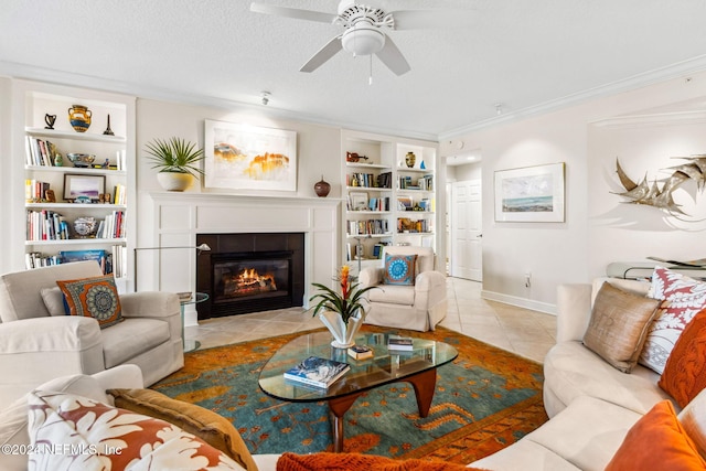 tiled living room with a tile fireplace, built in shelves, ceiling fan, ornamental molding, and a textured ceiling