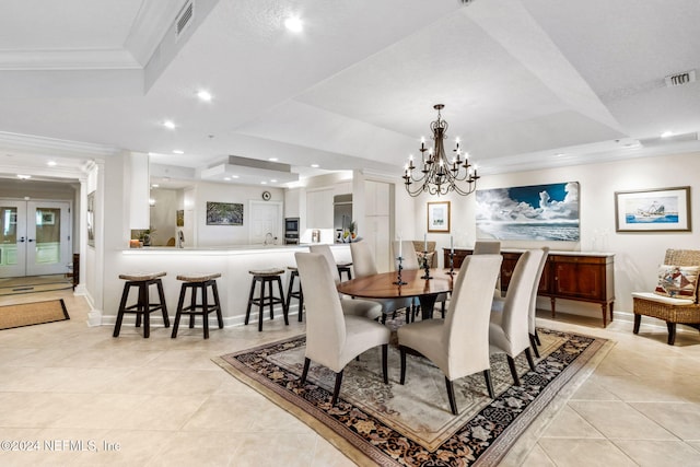 tiled dining room with a raised ceiling, crown molding, and an inviting chandelier