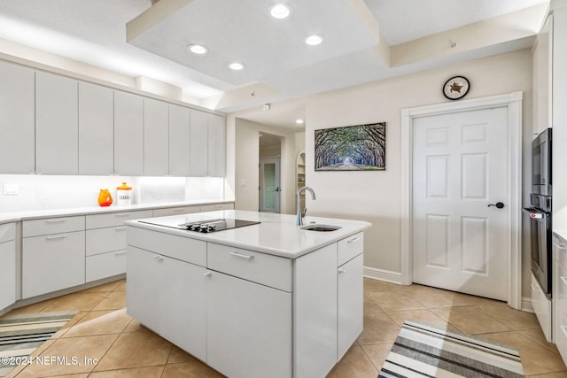 kitchen featuring white cabinetry, sink, a kitchen island with sink, light tile patterned floors, and black appliances