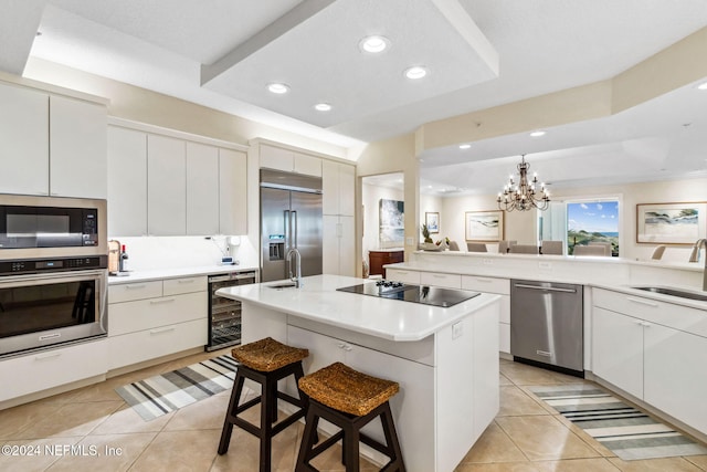 kitchen featuring a kitchen breakfast bar, beverage cooler, a kitchen island with sink, built in appliances, and an inviting chandelier