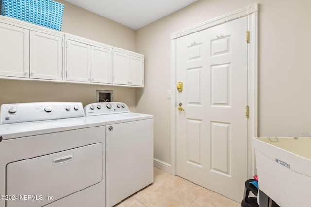 laundry room featuring washing machine and clothes dryer, light tile patterned floors, and cabinets