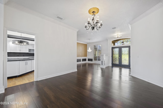 unfurnished living room with french doors, a textured ceiling, crown molding, a notable chandelier, and dark hardwood / wood-style floors