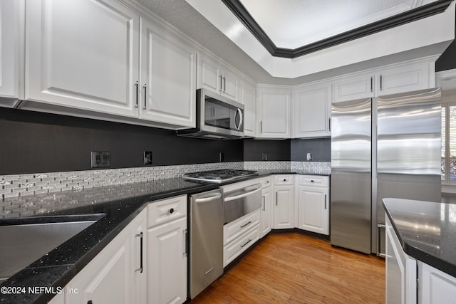 kitchen with light wood-type flooring, white cabinetry, appliances with stainless steel finishes, and dark stone counters