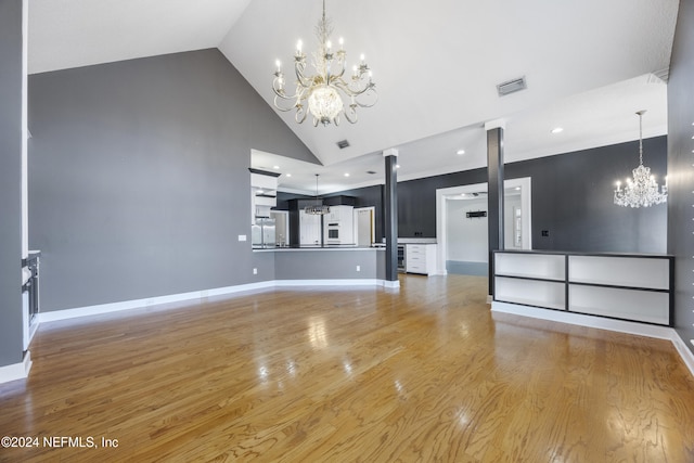 unfurnished living room with a notable chandelier, wood-type flooring, and high vaulted ceiling