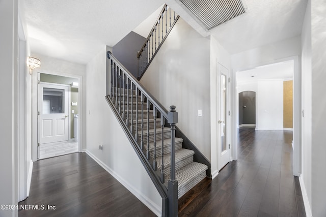 staircase with wood-type flooring and a textured ceiling