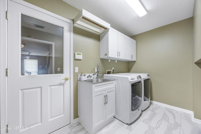 laundry area with cabinets, independent washer and dryer, a textured ceiling, and sink