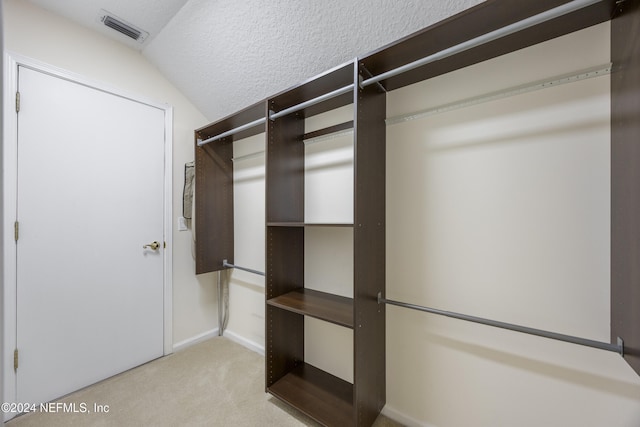 spacious closet featuring light colored carpet and vaulted ceiling