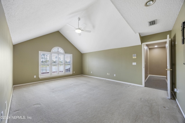 interior space featuring a textured ceiling, light colored carpet, vaulted ceiling, and ceiling fan