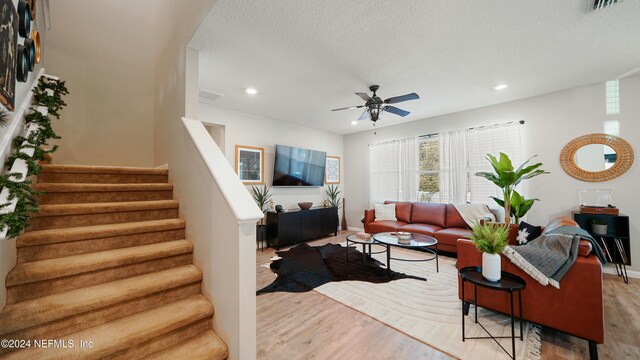 living room with wood-type flooring, a textured ceiling, and ceiling fan