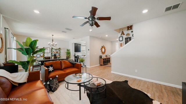 living room with ceiling fan with notable chandelier and light wood-type flooring