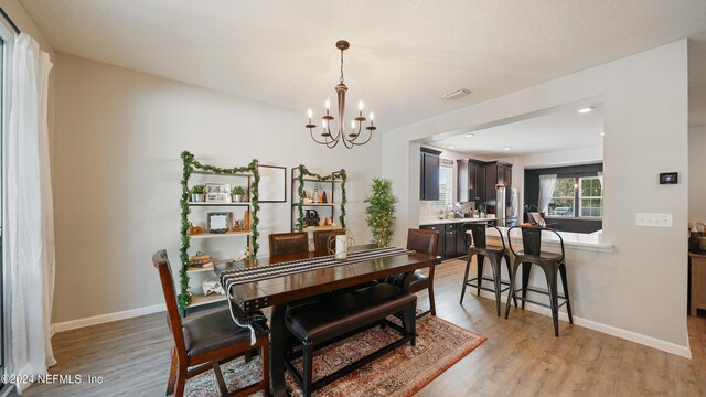 dining space with light wood-type flooring and an inviting chandelier