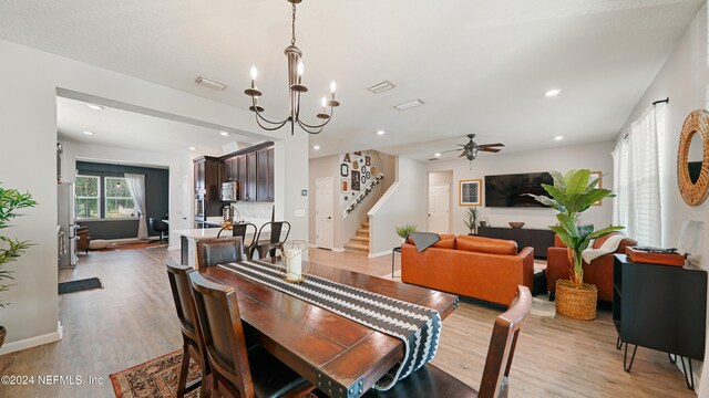 dining space with ceiling fan with notable chandelier and light hardwood / wood-style floors