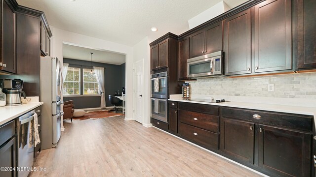 kitchen featuring pendant lighting, dark brown cabinets, appliances with stainless steel finishes, and light hardwood / wood-style flooring