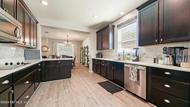 kitchen featuring backsplash, stainless steel appliances, an inviting chandelier, light hardwood / wood-style floors, and hanging light fixtures