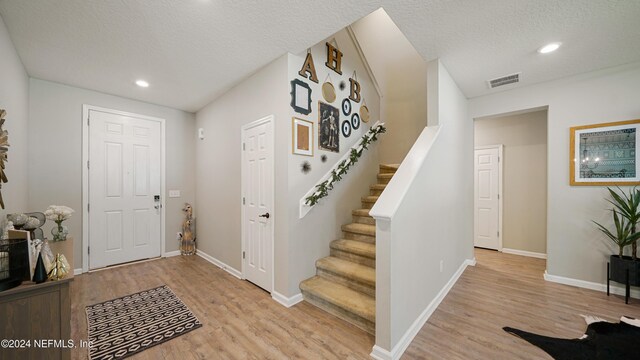 entryway featuring a textured ceiling and light hardwood / wood-style flooring