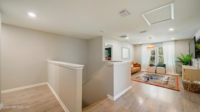 hall featuring light wood-type flooring and a textured ceiling