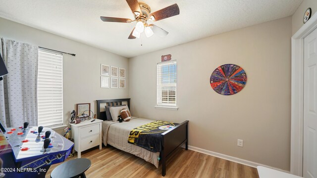 bedroom with a textured ceiling, light hardwood / wood-style flooring, and ceiling fan