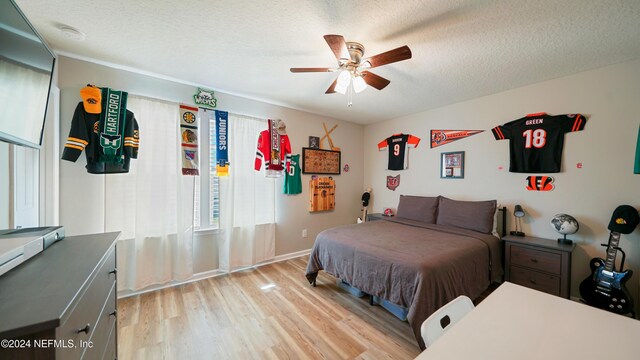 bedroom with a textured ceiling, light wood-type flooring, and ceiling fan