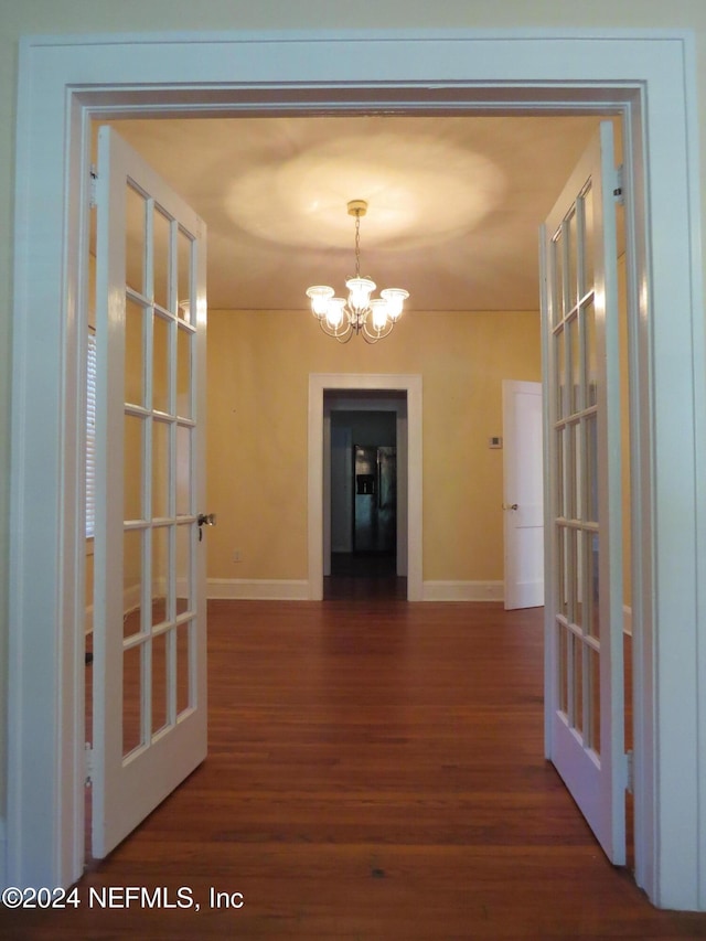 hall with french doors, dark wood-type flooring, and a chandelier