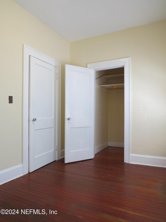 unfurnished bedroom with dark hardwood / wood-style floors and a closet